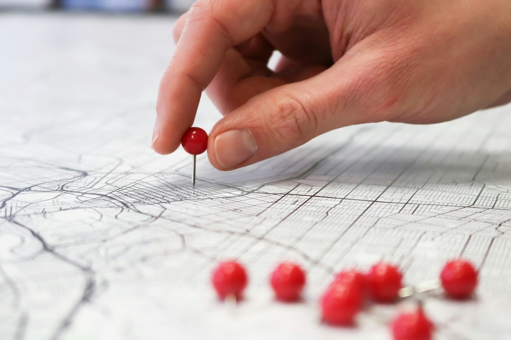 A hand placing pins on a map.