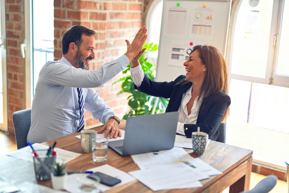 Two people working together and giving each other a high-five.